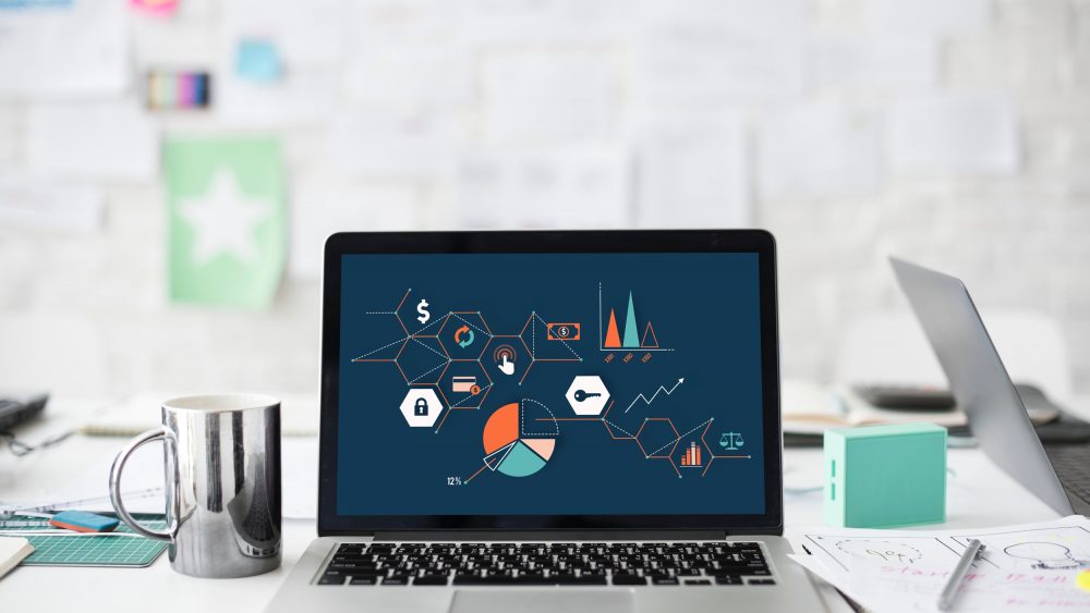 A laptop on a desk displaying various charts and graphs.