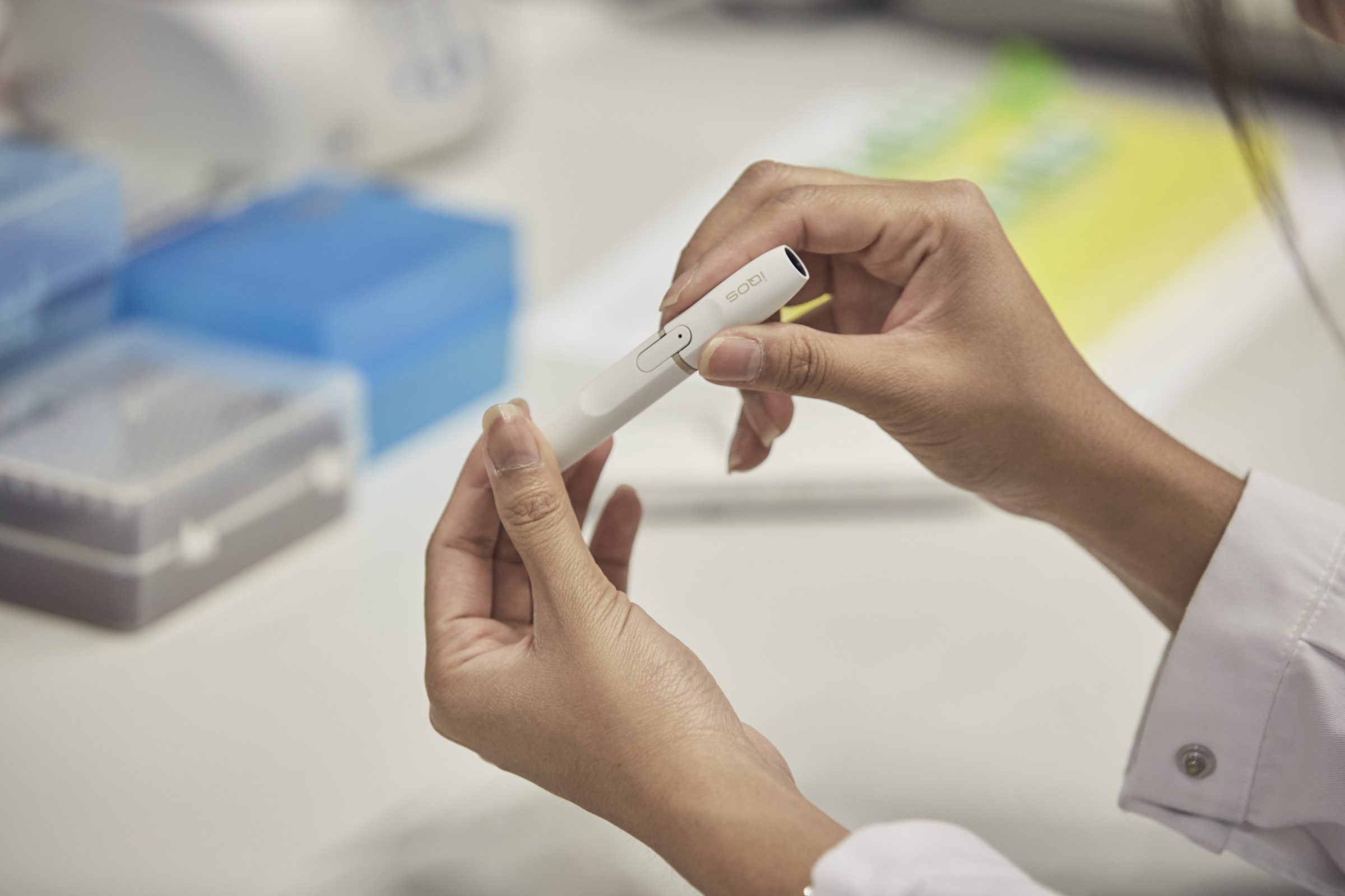 A scientist in a lab examines an IQOS vaporizer.