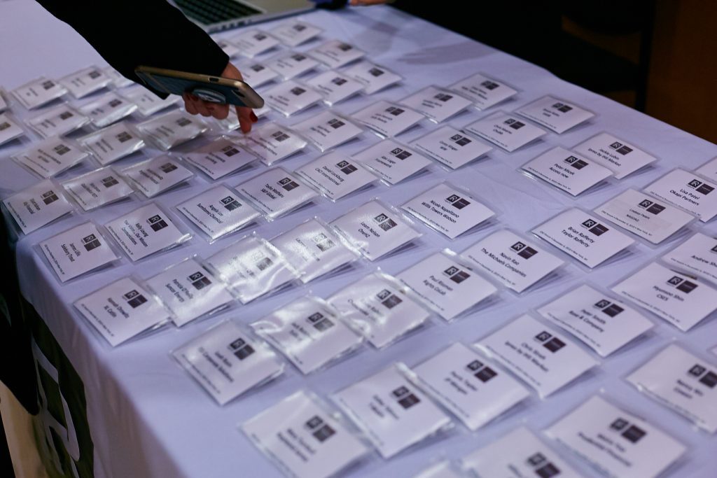 A conference attendee collects a name badge from a table.